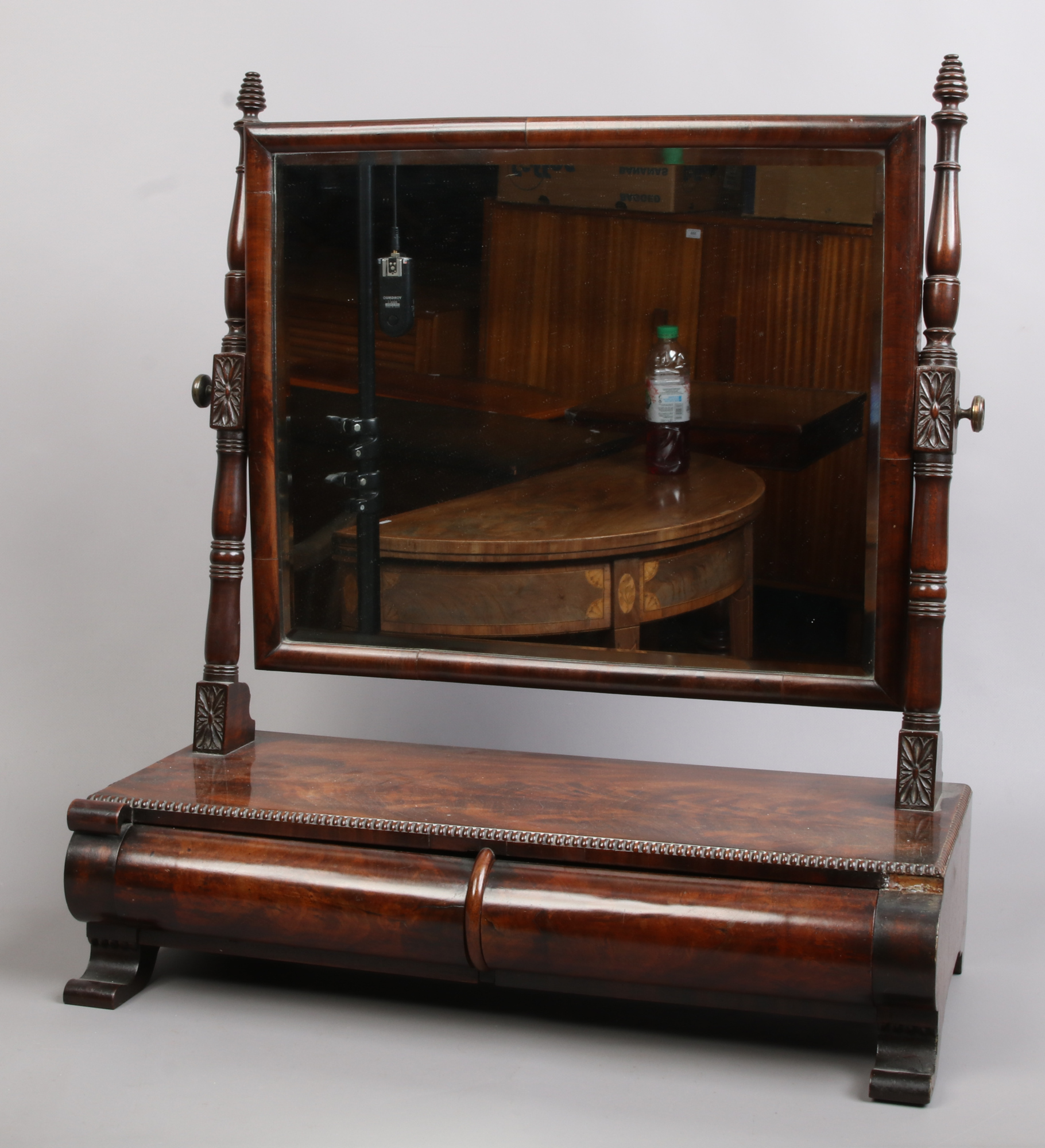 A Victorian figured mahogany two drawer toilet mirror with beaded mouldings and raised on scroll