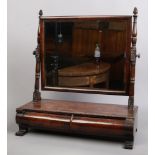 A Victorian figured mahogany two drawer toilet mirror with beaded mouldings and raised on scroll