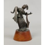 An Indian bronze figure of a woman dancing raised on a wooden plinth.