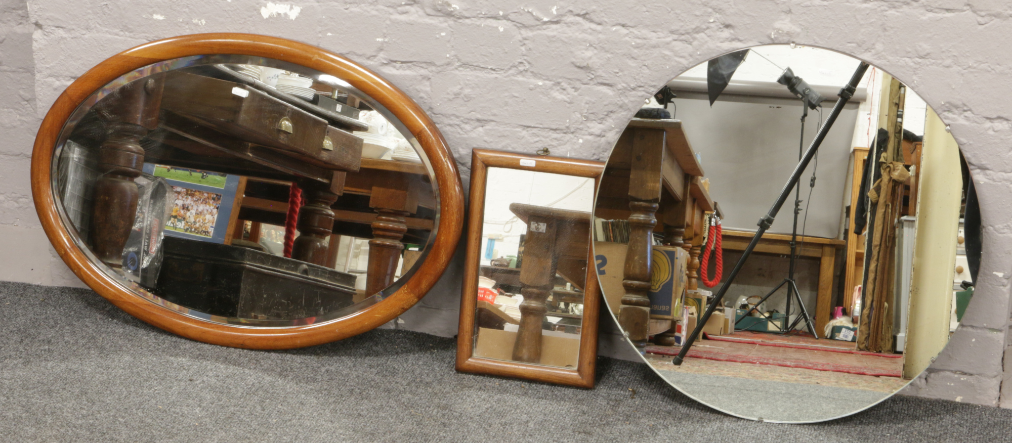 A circular hall mirror along with two mahogany framed mirrors.