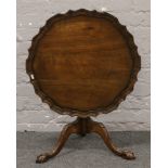 A carved mahogany scallop edge snap top occasional table raised on ball and claw feet.