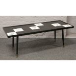 A tile top coffee table on tapering supports.
