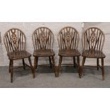 A set of four wheel back dining chairs.