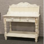 A painted washstand raised on turned supports with tile splash back and two drawers.
