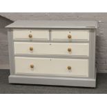 A painted grey chest of four drawers.