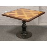 A parquetry inlaid table raised on cast iron centre pedestal base, 91cm x 91cm.