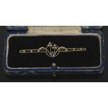 A cased Edwardian 15ct gold bar brooch set with sapphire and seed pearls.