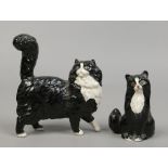 Two Royal Doulton models of black and white cats, one seated the other standing with raised tail.