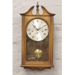 A Schmeckenbecher wall clock housing a three train movement chiming on a gong. With key and
