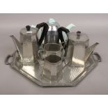 An Arts & Crafts Sheffield hand beaten pewter four part teaset on twin handed serving tray, along