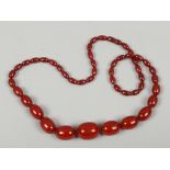 A string of vintage cherry amber Bakelite graduated ovoid beads with concealed clasps.