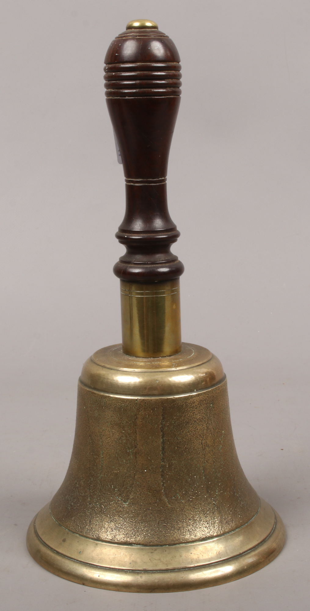 A brass bell with turned wooden handle.