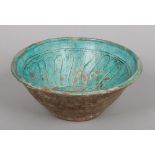 An antique Persian pottery bowl. Turquoise glazed and with incised decoration, 24cm diameter.