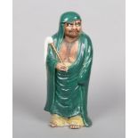 A Japanese Meiji period Satsuma figure of a bearded man, dressed in a flowing green robe and holding