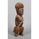 An African carved hardwood sculpture of a tribeswoman. With cowrie shell eyes, ropework coiffure,