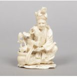 A Japanese carved ivory okimono. Formed as a figure seated with two toads and a with a pot of ruyi