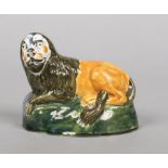 An early 19th century pearlware model of a recumbent lion. Press moulded and decorated in coloured