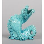 A Burmantofts Faience model of a grotesque dragon. In seated pose and decorated in turquoise