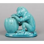 A Burmantofts Faience model of a monkey glazed in turquoise. Modelled in a seated position holding a