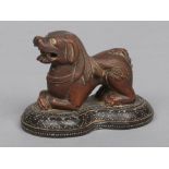 An 18th century eastern carved wooden model of a recumbent lion dog, possibly Burmese. Raised on a