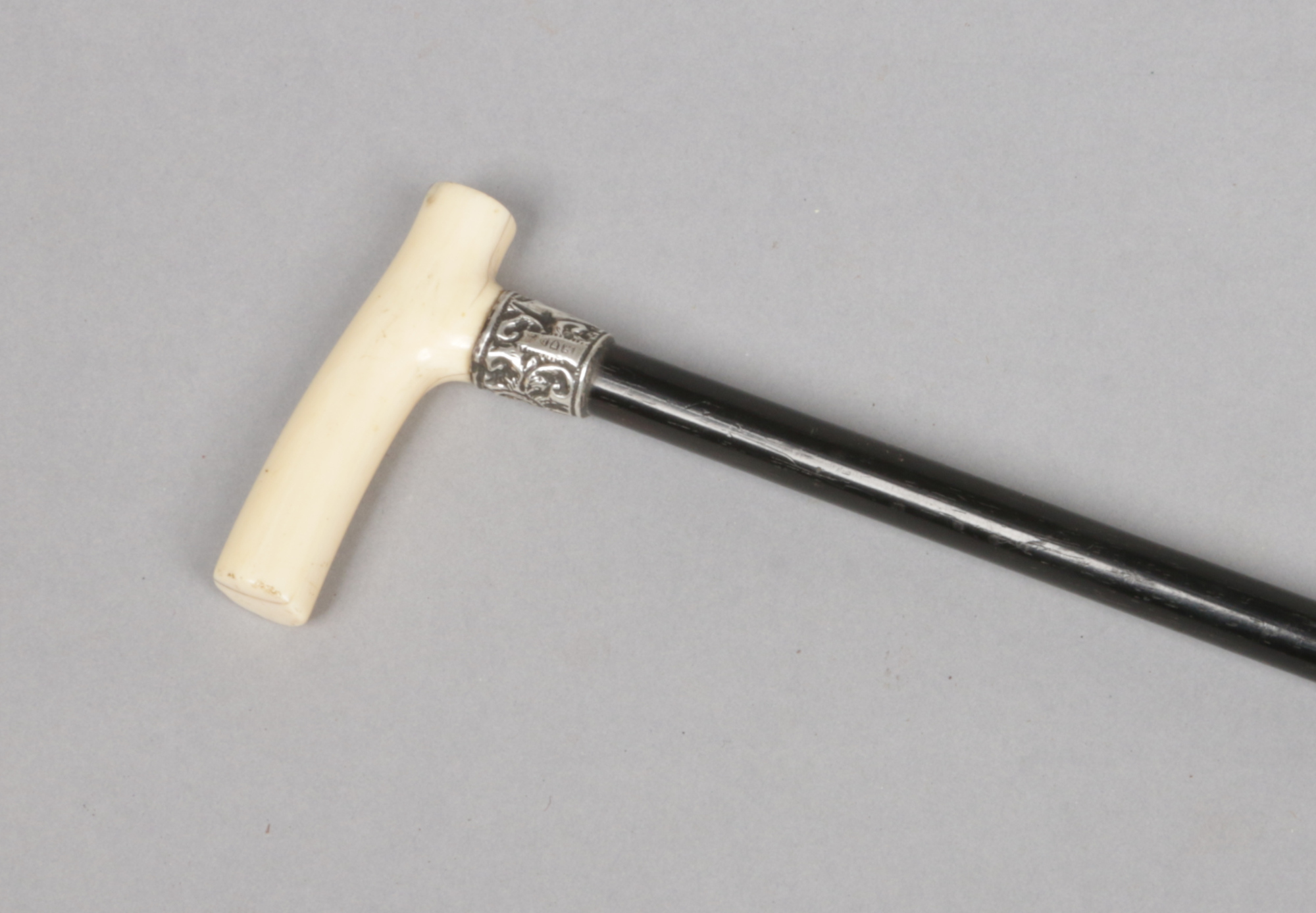 A ladies Victorian ebonized walking cane with silver collar and carved ivory grip. Total weight