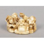 A Japanese Meiji period carved ivory netsuke. Formed as a seated group of figures eating. Signed,