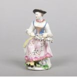 A Bow Commedia dell'arte figure of Columbine seated playing a hurdy gurdy. Painted in polychrome