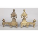 A pair of 19th century Neo-Classical bronze fire dogs with urn shaped finials.