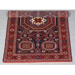 A hand knotted blue and red ground rug. With a medallion design and flower borders, 154cm x 202cm.