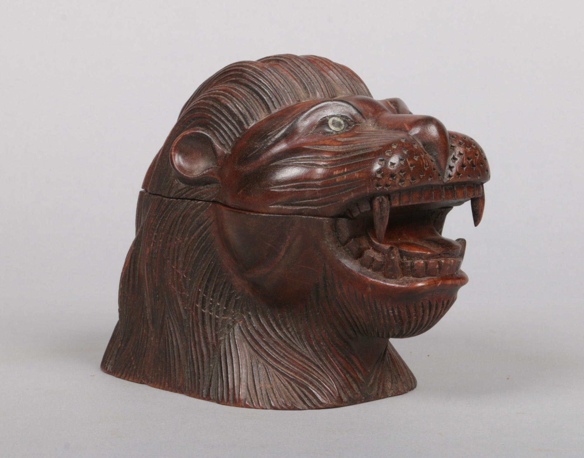 A zoomorphic carved hardwood tobacco jar in the form of a lions head and with mother of pearl