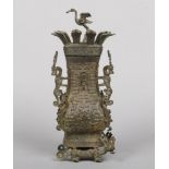 An archaistic Chinese bronze baluster shaped urn and cover. The finial formed as a standing crane,