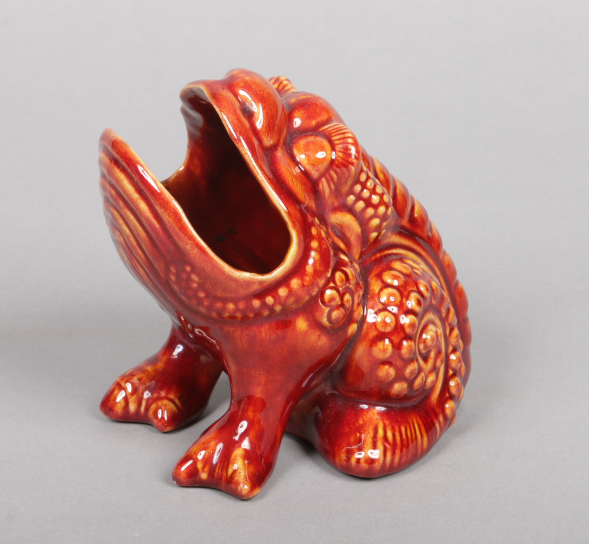 A Burmantofts Faience spoon warmer modelled in the form of a bull frog and decorated in red glaze.