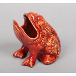 A Burmantofts Faience spoon warmer modelled in the form of a bull frog and decorated in red glaze.
