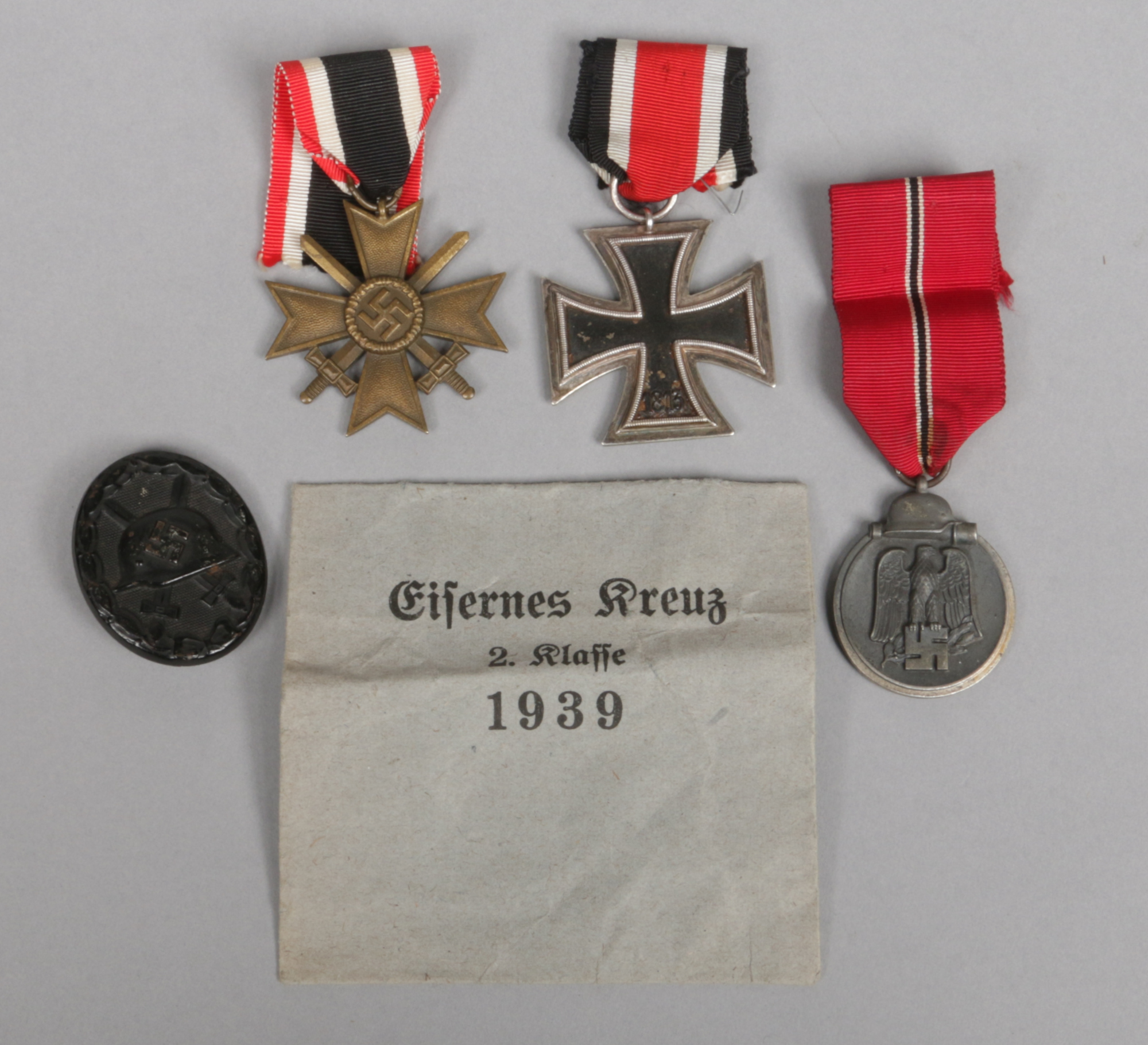 Three World War II German Third Reich medals and a badge. Iron Cross, War Merit Cross and Eastern