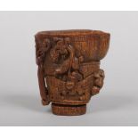 A Chinese carved horn libation cup. With incised key fret borders and carved with four mythical