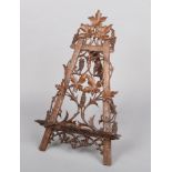 A Black Forest carved walnut book stand / easel. Adorned with fruiting vines, 65cm.