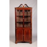 A 19th century mahogany floor standing corner cupboard. With swan neck pediment, strung inlay and