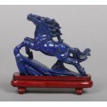 A 20th century Chinese carved lapis lazuli model of a horse raised on a wooden plinth, 13.5cm.