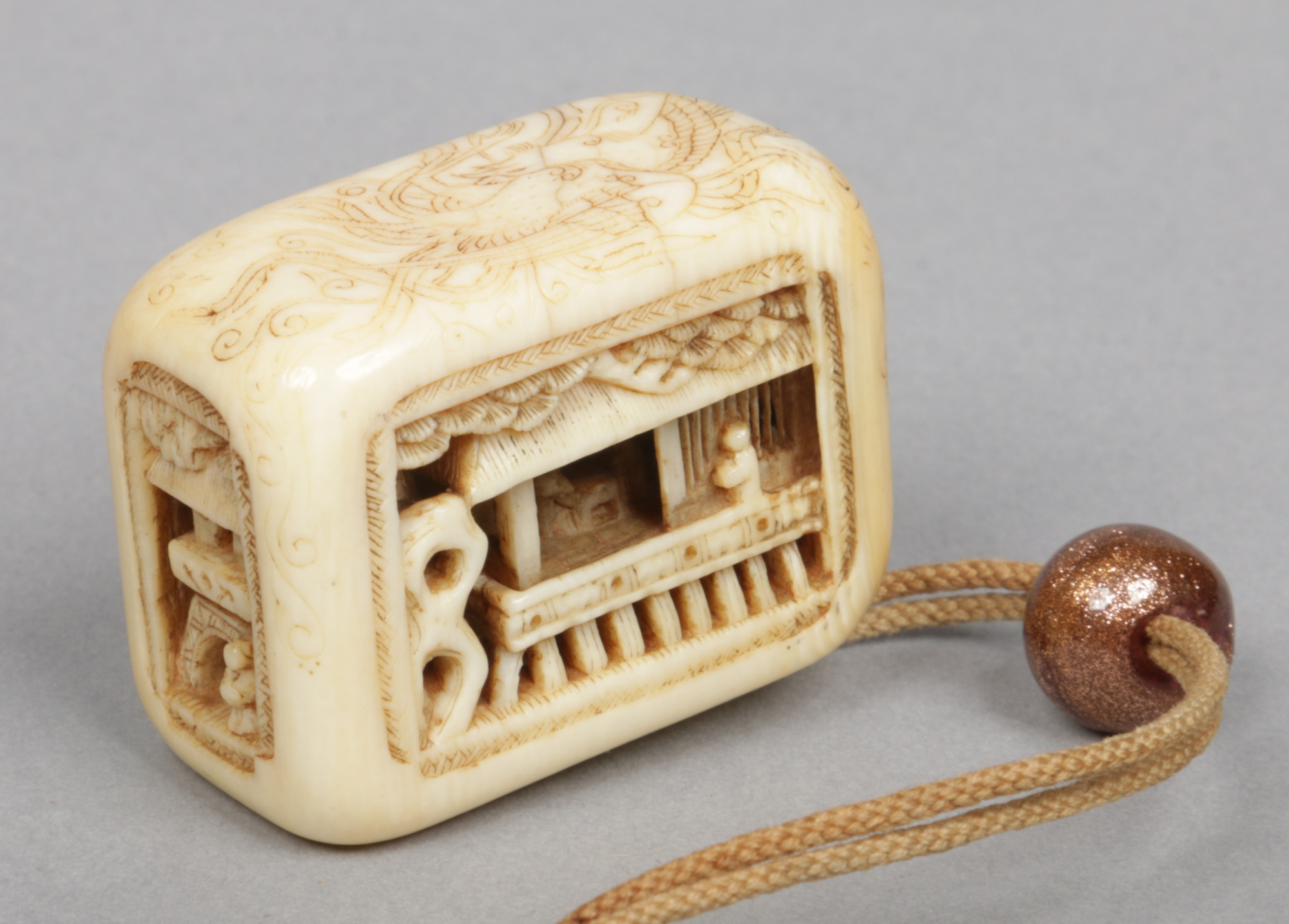 A Japanese Meiji period carved ivory netsuke decorated with figures and buildings and incised with a - Image 2 of 2
