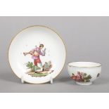 A Meissen teabowl and saucer. With gilt rims and painted in coloured enamels with figures at various