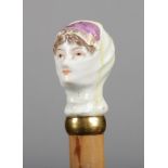 An 18th century porcelain cane handle mounted on a parasol. Formed as a veiled maiden and coloured