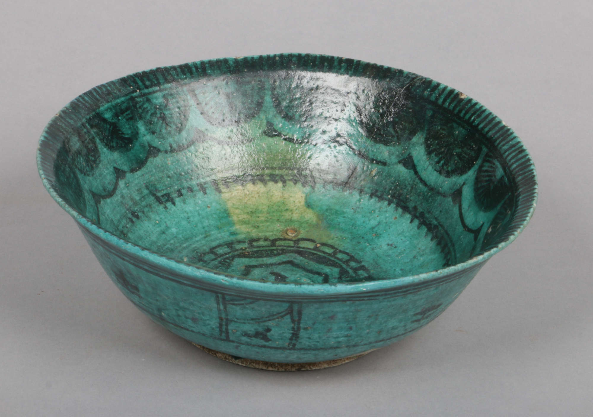An antique Persian pottery bowl. Green glazed and with stylized penwork decoration, 21.5cm