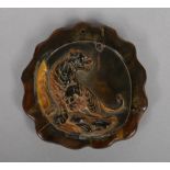 A Chinese carved horn amulet with lobed rim and decorated in relief with a tiger, 7.5cm wide.