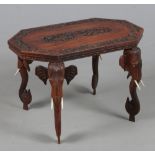 An Indian carved hardwood occasional table of canted rectangular form and raised on elephant mask