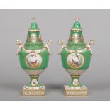 A pair of twin handled lidded mantel urns. Green ground, with gilt decoration and painted with