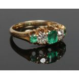 A Victorian emerald and diamond five stone ring in a boat shaped setting. The two diamonds