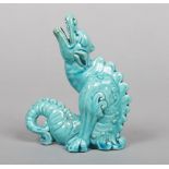 A small Burmantofts Faience model of a grotesque dragon. Seated and with its head tilted back,