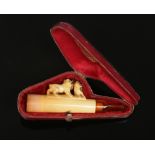 A cased carved meerschaum cheroot holder surmounted by three pugs, 9.5cm.