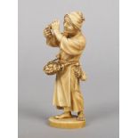 A Japanese Meiji period ivory okimono. Carved in the form of a street trader with a basket of