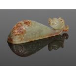 A Chinese archaistic carved celadon jade belt buckle with russet suffusions. The pommel carved in